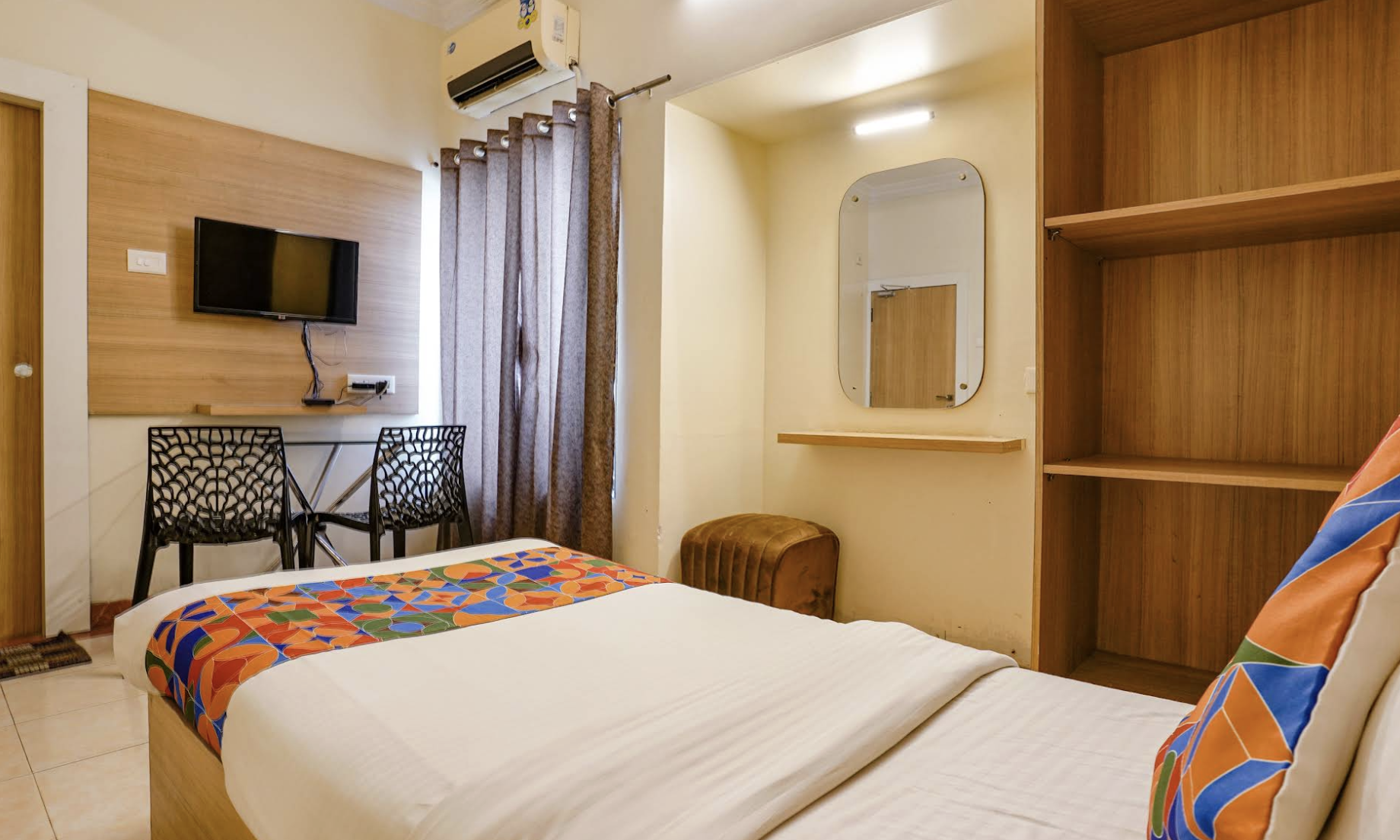 Hotel room with bed, TV, mirror, and wardrobe